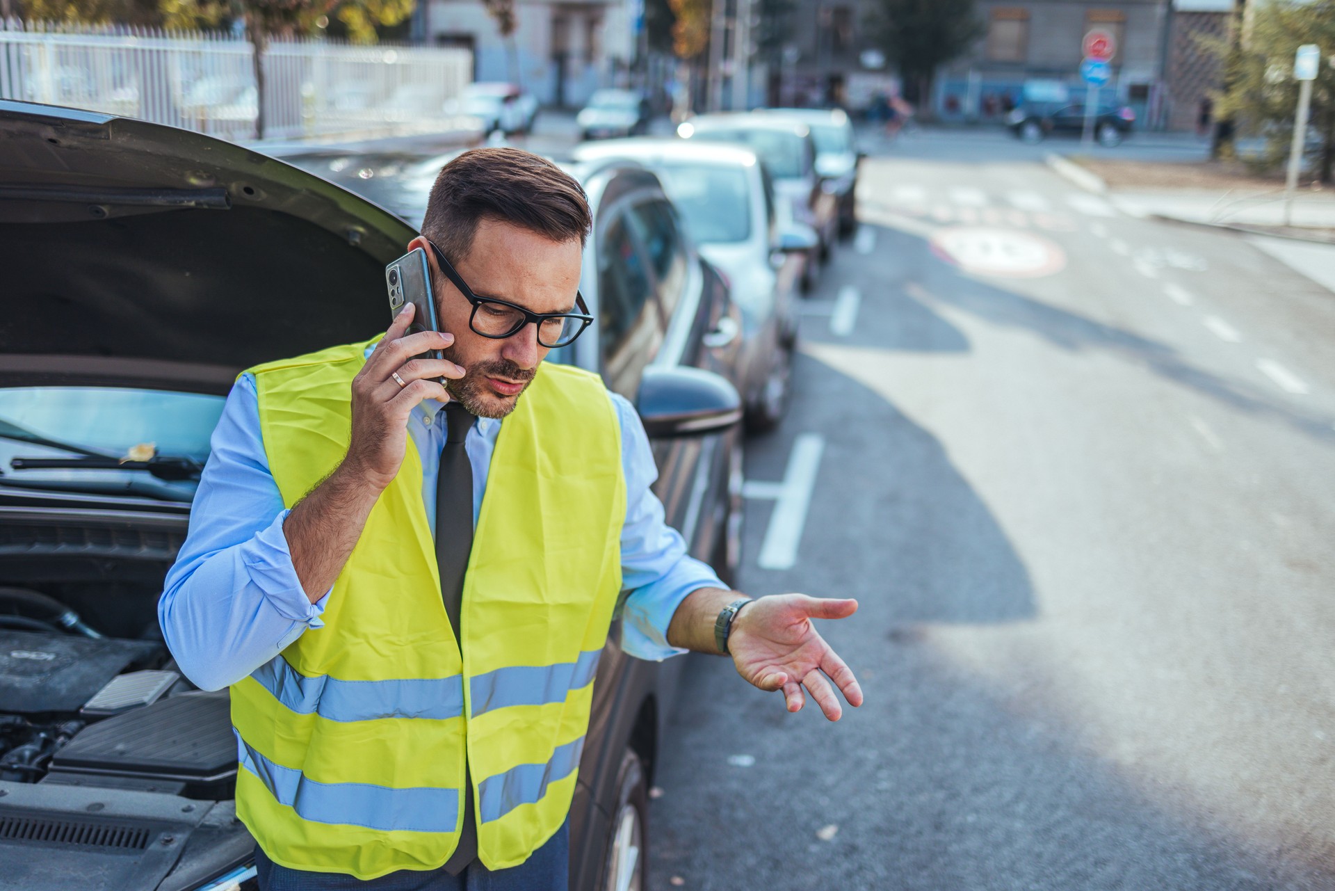 Man in Safety Vest Making Call After Car Breakdown